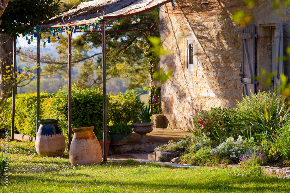 Terrasse ombragée dans le jardin d'une maison en Quercy, France. - obrazy, fototapety, plakaty 