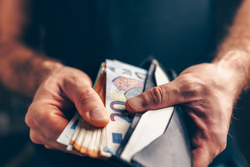 Stack of euros in a wallet - purchasing power - male hands closeup