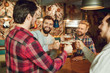 © Studio Romantic - Group of happy friends clinking glasses with beer at a sports bar.