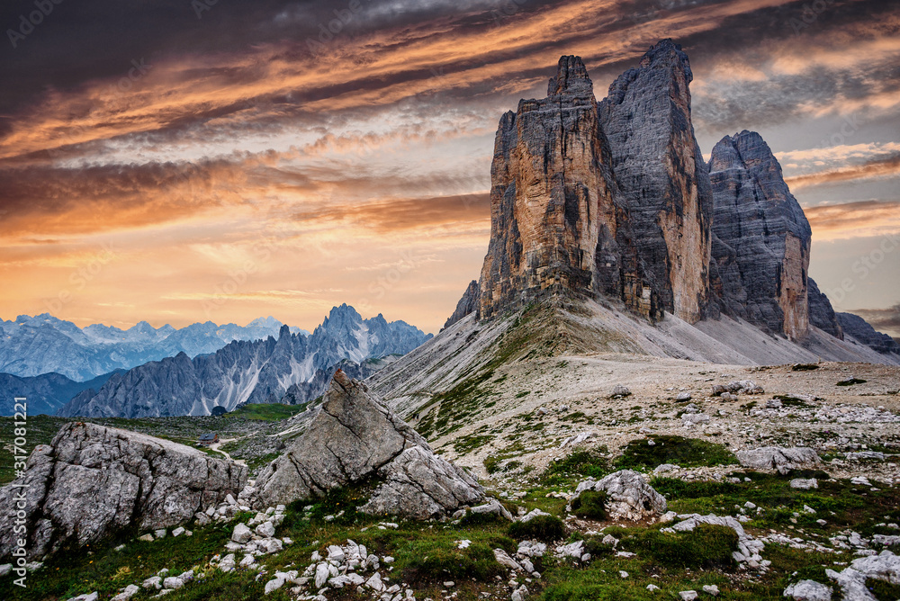 Awesome alpine highlands during sunset. Amasing nature landscape. Tre Cime di Laveredo, three spectacular mountain peaks with colorful sky, Dolomites Alps, South Tyrol, Italy. Picture of wild area. - obrazy, fototapety, plakaty 