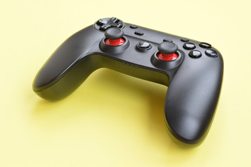 Modern black video game controller on yellow background. Online video game players community concept