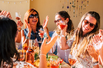 Young group of women have fun and laugh a lot during lunch at restaurant or home all together in friendship - female people friends with food and drinks