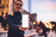 © BullRun - Selective focus on blank smartphone gadget with copy space area for advertising or content text on publicity area, millennial woman showing website on mock up touchscreen of cellphone device