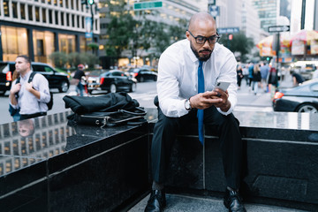 Wall Mural - Elegant businessman man surfing mobile sitting on street stairs