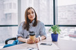 © BullRun - Stylish woman with takeaway beverage in office