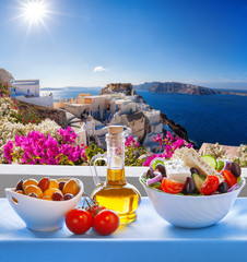 Greek salad against famous church in Oia village, Santorini island in Greece