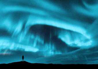 Wall Mural - aurora borealis and silhouette of standing man on the hill. lofoten islands, norway. aurora and alon