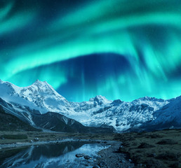 Wall Mural - aurora borealis over the snowy mountains, coast of the lake and reflection in water. northern lights