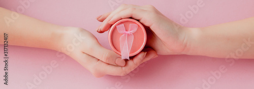 Fotografía Round pink gift box in women's hands on a pink background