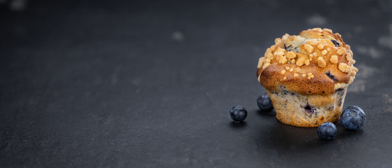 Fresh made Blueberry Muffins on a slate slab (close-up shot; selective focus)