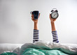 © New Africa - Woman with cup and alarm clock lying in bed, closeup. Morning time