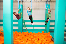 Three Boys Going Through Obstacle Course Over Foam Pit