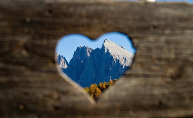 Sticker - Selective focus shot from a heart-shaped hole of mountains in the distance in dolomite Italy