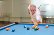 © feeling lucky - Indoor shot attractive bearded senior caucasian man in white shirt looking and playing billiard or snooker ball with concentration and serious face during the game in sport club. (Focus on his hand)