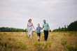 © Вероника Преображенс - The boy leads the hands of his parents. Happy family in the fresh air. A family of three walking around the field