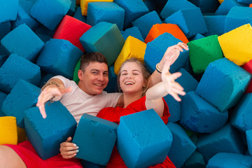 Fitness, fun, leisure and sport activity concept - Funny happy man and woman having fun on a trampoline indoors