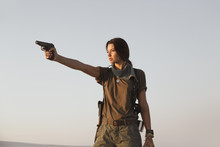 Woman Standing With A Gun Outdoors In Desert