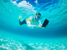 Snorkelling Businessman In Shirt And Tie And Matching Fins Using A Tablet Computer While Swimming Under Water In Tropical Turquoise Sea