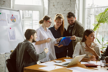 Wall Mural - One family. Group of young business professionals having a meeting. Diverse group of coworkers discuss new decisions, plans, results, strategy. Creativity, workplace, business, finance, teamwork.