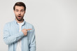 © fizkes - Excited young man standing aside, pointing at empty copy space.