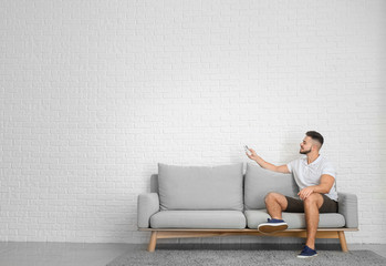 Wall Mural - Young man switching on air conditioner at home