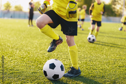 Soccer players on training field on football camp. Kids practice soccer on su...