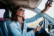 Young Beautiful Woman Driving A Car And Adjusting Rear Mirror. Travel Concept