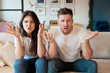 © studioprodakshn - young couple man and woman sitting on the sofa both looking astonished, grimacing mood