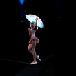 happy acrobat in costume holding umbrella and walking on rope