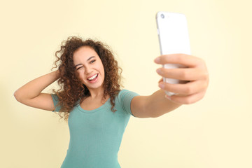 Poster - Beautiful young woman taking selfie on light background