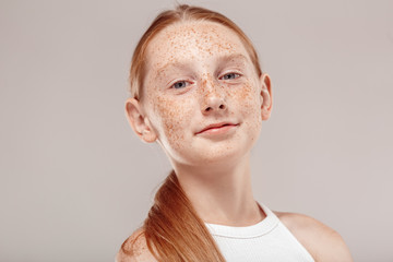 Wall Mural - Inclusive Beauty. Girl with freckles standing isolated on grey smilign confident bottom view