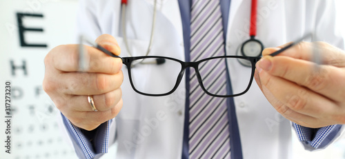 Fotografía Male medicine doctor hands giving pair of black glasses