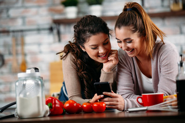 Sisters cooking together. Two friends having fun in kitchen. 