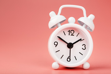 White retro alarm clock on pink background. Concept of time with free space for text.