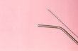 Metal, bendy drinking straw and steel cleaning brush on pink background. Aluminum stainless reusable bar equipment for drink alcohol cocktails, water or lemonade. Eco friendly alternative