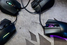 Close-up group of modern gaming mouse on black color with LED RGB light show status on working mode placing on gaming mouse pad on top-view, e-sport concept