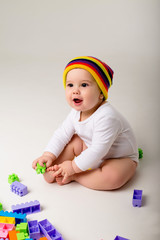 Wall Mural - baby boy 9 months old playing with a multi-colored constructor on a white background. the concept of development of the child, space for text