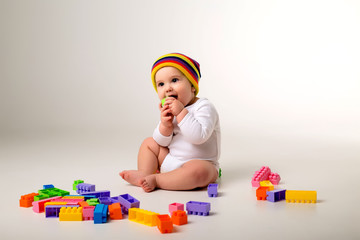 Wall Mural - baby boy 9 months old playing with a multi-colored constructor on a white background. the concept of development of the child, space for text