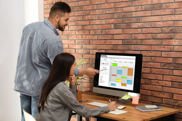 Canvas Print - Colleagues working with calendar app on computer in office