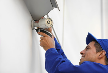 Poster - Technician installing CCTV camera on wall outdoors