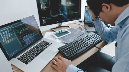 Wall Mural - programmer working on computer in it office typing data coding in software and checking code on comp