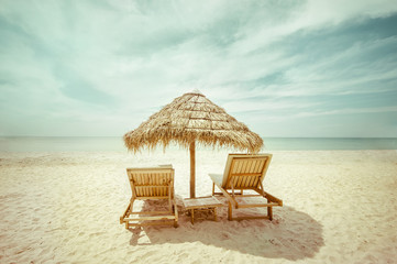 Tropical beach with thatch umbrella and chairs for relaxation