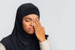 Black muslim girl in hijab suffering from eye pain, touching eyelid