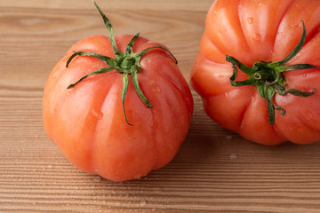 Top view of two pink tomatoes with water drops on wooden table in horizontal