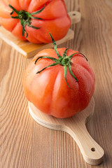 Top view of two pink tomatoes with water drops on wooden boards and table in horizontal with selective focus