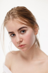 thoughtful teen model wearing shirt posing with bare shoulders, piercing in nose and earrings. caucasian skinny young female isolated on white background. sensual natural pretty girl poses in studio