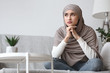© Prostock-studio - Thoughtful unhappy arabic woman in hijab sitting on couch at home