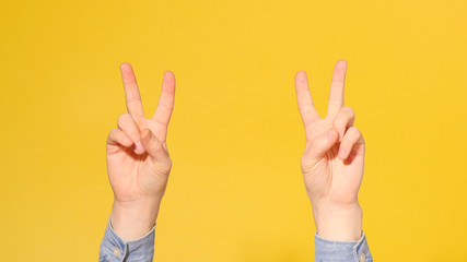 Man Hand Showing Victory Sign with Fingers Isolated on yellow Background