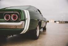 Closeup Shot Of A Green Muscle Car On A Blurred Background
