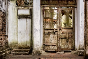 Wall Mural - Ancient wooden gate in an old building with weathered walls